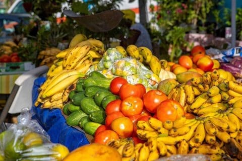 A colorful market display of bananas, tomatoes, and other fresh fruits and vegetables.